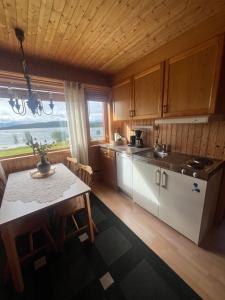 a kitchen with wooden cabinets and a table and a window at Senja seaside retreat in Senja