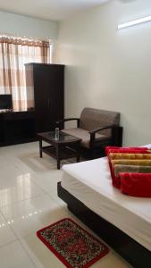 ein Schlafzimmer mit einem Bett, einem Stuhl und einem Tisch in der Unterkunft Well Park Resort in Cox's Bazar