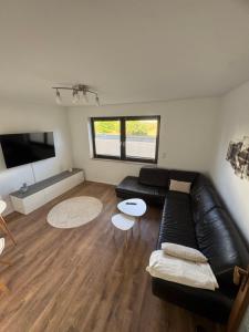 a living room with a black leather couch and a table at HabichtsNest Stockum in Sundern
