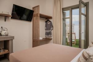 a bedroom with a bed and a tv and a window at JUNO Collection Residences in Pythagoreio