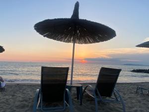 two chairs and an umbrella on the beach at Bylis Rooms in Golem