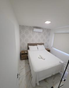 a bedroom with a white bed and a white wall at Apartamento Crisalidas em Foz in Foz do Iguaçu