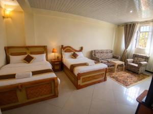 a bedroom with two beds and a couch and a chair at Avi Guest House in Addis Ababa