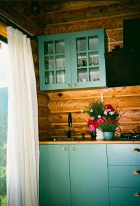 a kitchen with blue cabinets and a sink with flowers at OHANA Cottages in Merisi in Merisi