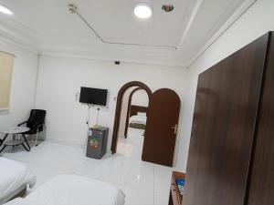 a bedroom with a bed and a door and a chair at فندق فاديه الذهبي in ‘Ushayrah