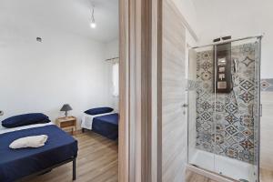 a bedroom with two beds and a glass shower at Ammentos La Casa di Rosa in Orgosolo