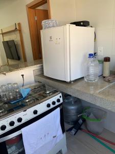 a kitchen counter with a stove and a white refrigerator at Apartamento central in Domingos Martins