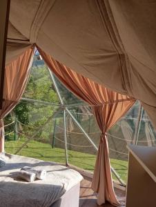 a bed in a tent with a large window at Drivibe Glamping, Goražde in Goražde