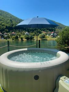 a hot tub with an umbrella next to a river at Drivibe Glamping, Goražde in Goražde +4 photos