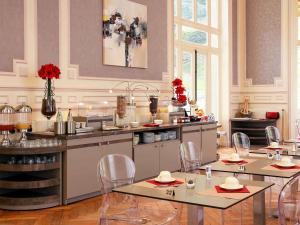 a kitchen with tables and chairs in a room at Mercure Saint Nectaire - Spa & Bien-Être in Saint-Nectaire