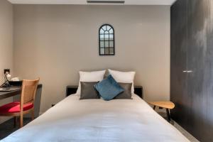 a bedroom with a bed with a desk and a chair at Hôtel & Restaurant La maison des blés in Boutervilliers +58 photos