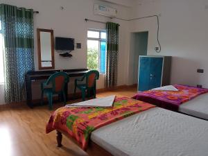 a bedroom with two beds and a desk and a mirror at BBL Resort in Bokākhāt