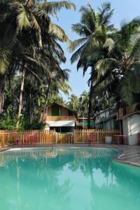 a swimming pool in front of a resort with palm trees at Betel Leaf Resort in Māhīm