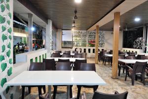 a restaurant with white tables and chairs in a room at Betel Leaf Resort in Māhīm