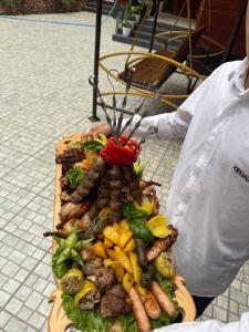 a person holding a plate of food with meat and vegetables at Oqtoshsoy in Oqtosh