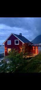 a red house with lights on the side of it at Modern Ocean Escape, Lofoten in Sund