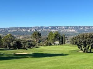 a green golf course with mountains in the background at LES CISTES in Mallemort +23 photos