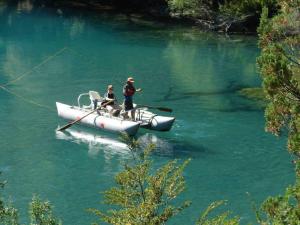 two people on a boat on a river in the water at CASA Los Tres Picos in Cholila