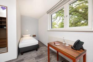 a bedroom with a bed and a desk with a telephone at Hotel Christophorus in Berlin