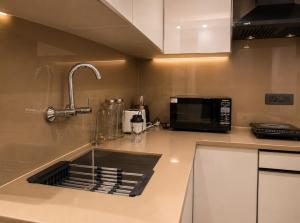 a kitchen counter with a sink and a microwave at Lime Tree Hotel Golf Course Road, Gurgaon in Gurgaon