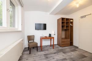 a room with a table and a chair and a television at Hotel Christophorus in Berlin