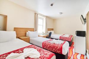 a hotel room with two beds and a television at Cranbrook Hotel in Ilford