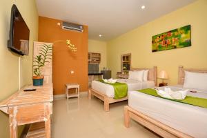 a bedroom with two beds and a television in it at The Rani Garden Bed & Breakfast in Denpasar