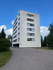 a large white building with a parking lot at Kumpukuja apartment in Kouvola