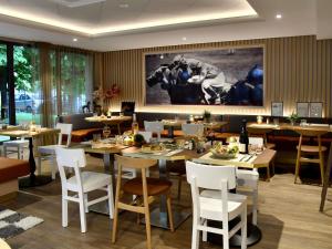 a restaurant with tables and chairs and a large painting on the wall at ibis Maisons Laffitte in Maisons-Laffitte