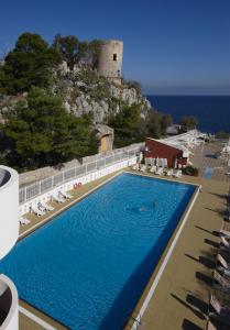 a swimming pool with chairs and a castle in the background at Splendid Hotel La Torre in Mondello