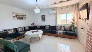 a living room with a black couch and a table at marhaba apartement in Oujda