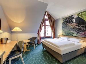 ein Hotelzimmer mit Bett, Tisch und Stühlen in der Unterkunft Mercure Hotel Erfurt Altstadt in Erfurt + 156 Fotos