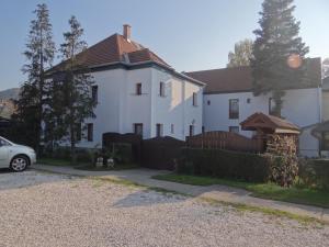 ein weißes Haus mit einem Zaun davor in der Unterkunft Holló Panzió in Visegrád