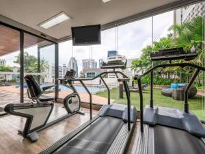 a gym with cardio equipment and a large window at Grand Mercure Bangkok Asoke Residence in Bangkok
