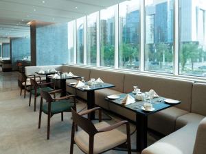 a restaurant with tables and chairs and windows at Novotel Riyadh Al Anoud in Riyadh