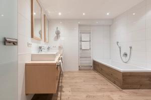 a white bathroom with a tub and a sink at Hotel Albona in Ischgl
