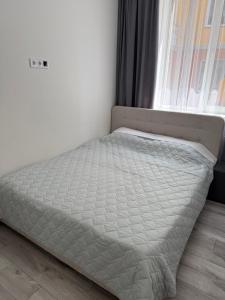 a bed in a room next to a window at Морской Двор in Chornomorsk