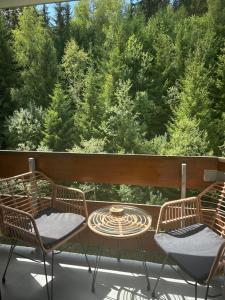 two chairs and a table on a balcony with trees at B&B cot in La Ferrière