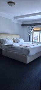 a bedroom with a large bed with white sheets and pillows at Kaa Highway Hotel Mukono in Mukono