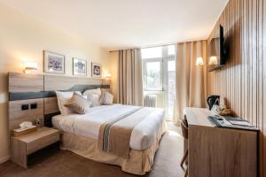 ゲブヴィレールにあるThe Originals City Hotel de l Ange Guebwillerのベッドと机のあるホテルの部屋
