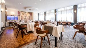 ゲブヴィレールにあるThe Originals City Hotel de l Ange Guebwillerの窓のある部屋にテーブルと椅子が置かれたレストラン