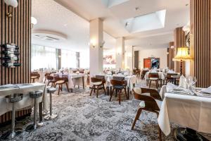 ゲブヴィレールにあるThe Originals City Hotel de l Ange Guebwillerの白いテーブルと椅子が置かれたダイニングルーム