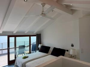 a white bedroom with a bed and a balcony at Lake View Apartments in Acquaseria
