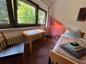 a small room with a bed and a table and window at Waldgarten Marienau in Höchenschwand
