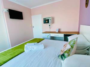 a bedroom with a white bed with a tv on the wall at Clearview Estuary Apartments in East London