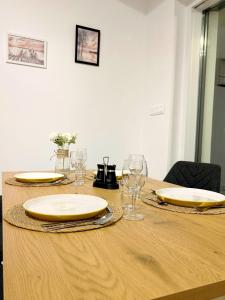 a wooden table with two plates and glasses on it at Helikon Terasz Apartman in Keszthely +24 photos