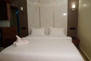a large bed with white sheets and pillows at Hotel Uasa Kesari Premium in Jājpur