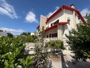 a white building with a red roof and some bushes at Telesico Residencia in Pombal