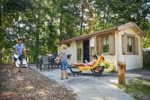 a woman sitting in a hammock in front of a house at RCN Vakantiepark de Schotsman in Kamperland