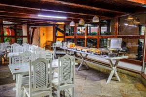 a restaurant with white chairs and a table with food at Rede Andrade Galeão in Porto Seguro